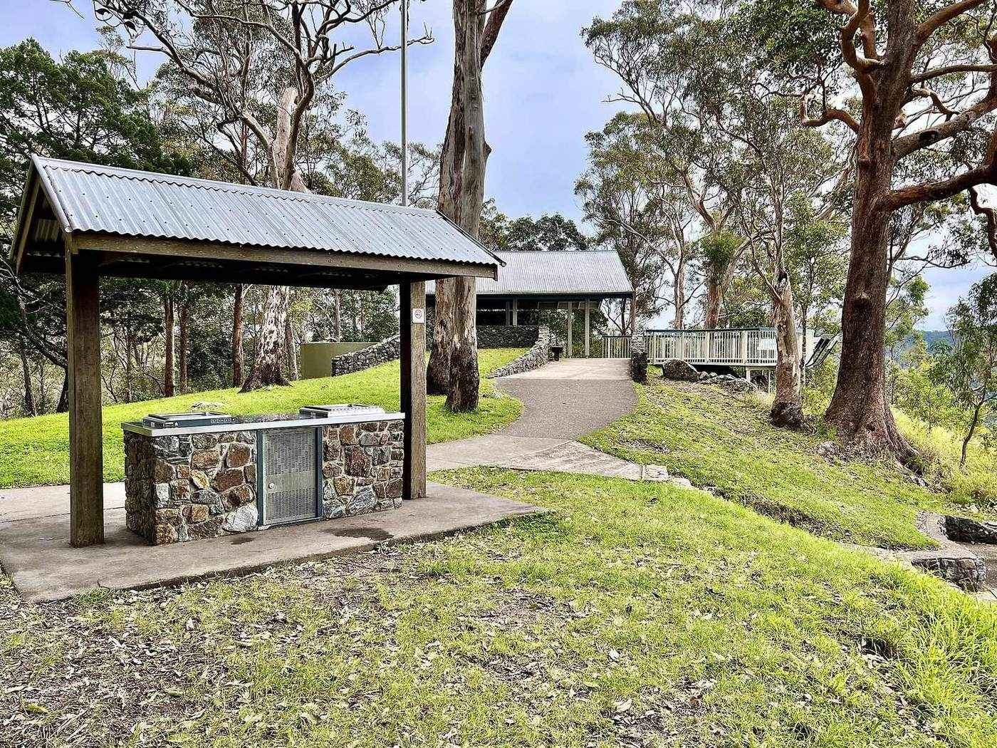 A grassy lookout with picnic shelter at the edge of the forest, looking east over a hazy valley