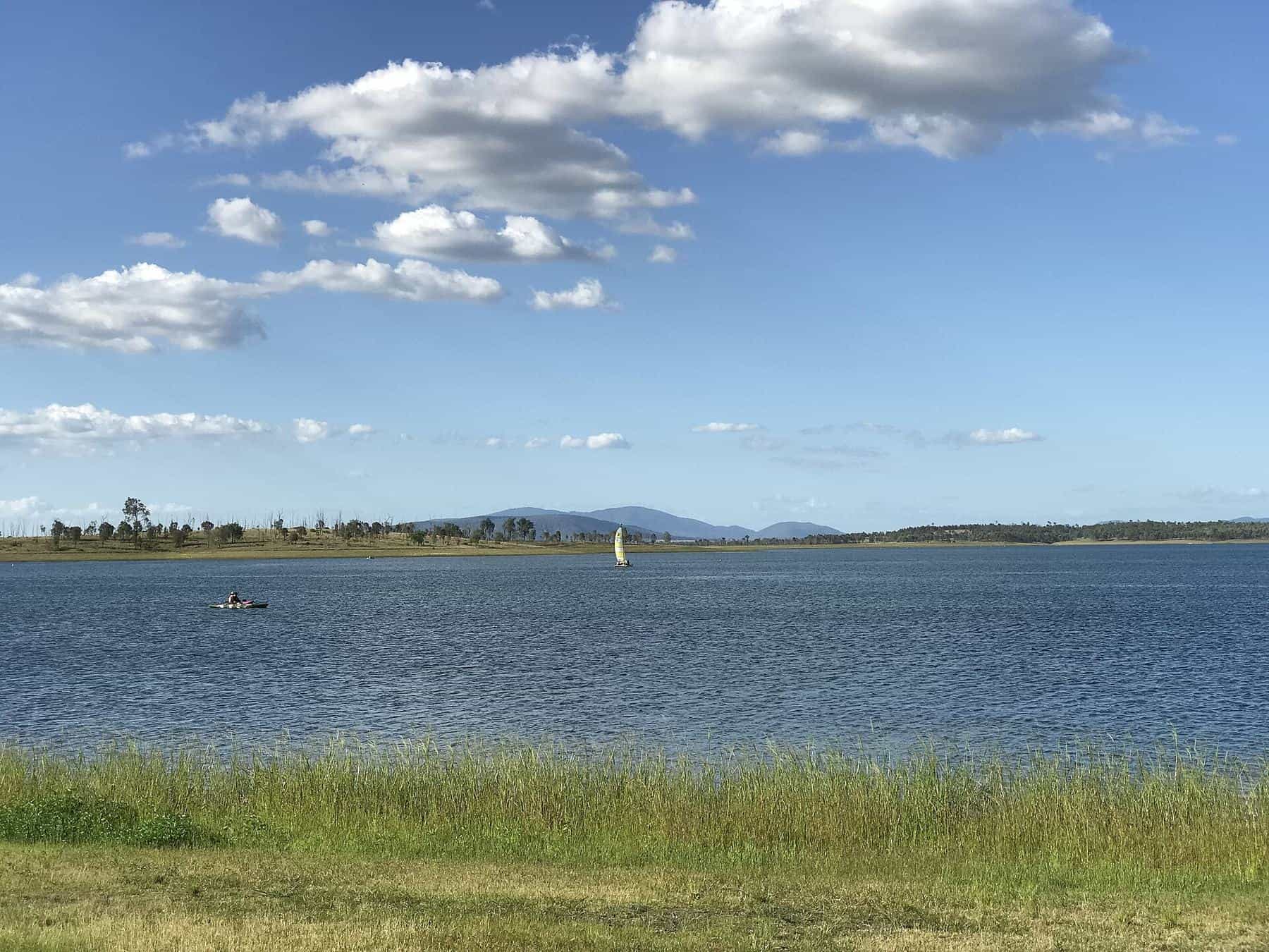 The calm waters of Lake Wivenhoe stretching to low hills under a blue sky